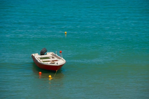 Small fishing boat on the sea in a summer day.boat is standing docked and reflecting in blue and green sea water in sunny summer day