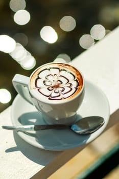 Hot coffee cappuccino in white cup.Morning coffee. white cup of latte hot coffee with leaf, flower pattern, latte art. Coffee Mug on outdoor
