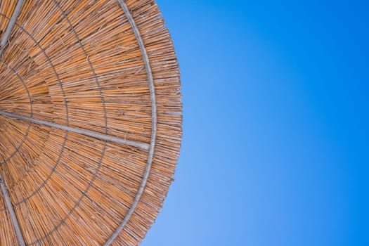Straw roof of sun umbrella against the blue sky. Vacation topic.