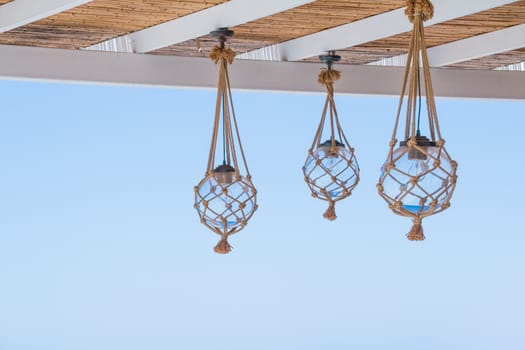 Straw cover the roof of a seaside terrace or veranda with hanging lantern and beautiful view of coastal landscape.