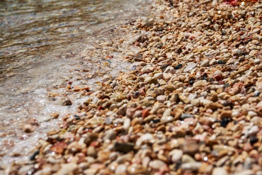 sea waves with many beautiful beach pebbles texture background