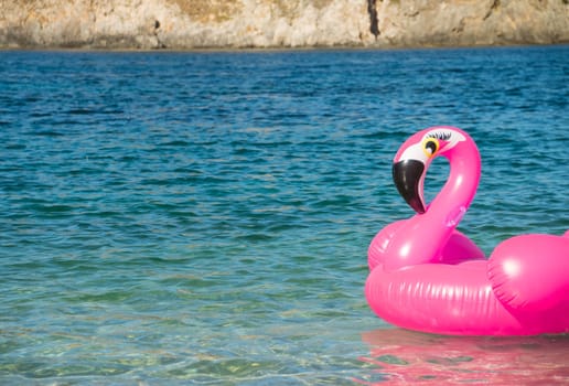 beach with a swim ring in the shape of a pink flamingo