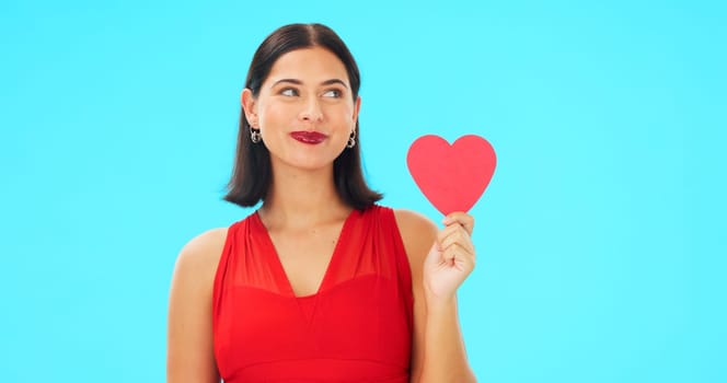 Paper heart, happy woman and face on blue background, studio and backdrop. Portrait of female model in red dress with shape of love, trust and romance for valentines day, flirting and elegant smile.