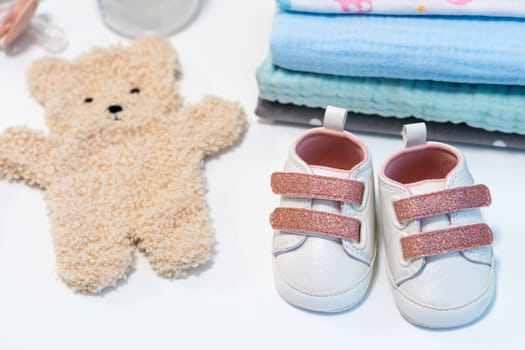 Baby girl pink shoes with other newborn baby accessories on white surface