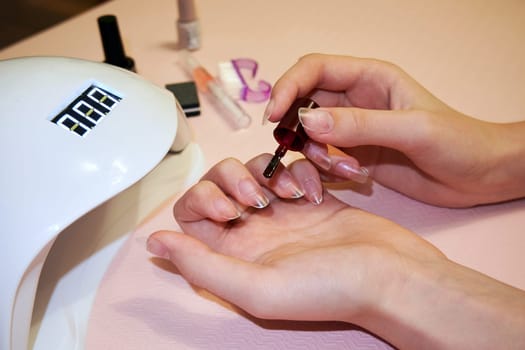 Applying nail polish on false nails close-up