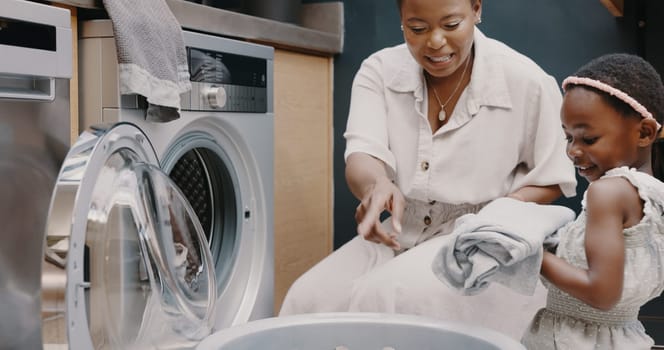 Laundry, mother and child helping with folding of clothes together in a house. Happy, excited and young girl giving help to her mom while cleaning clothing from a washing machine in their home.