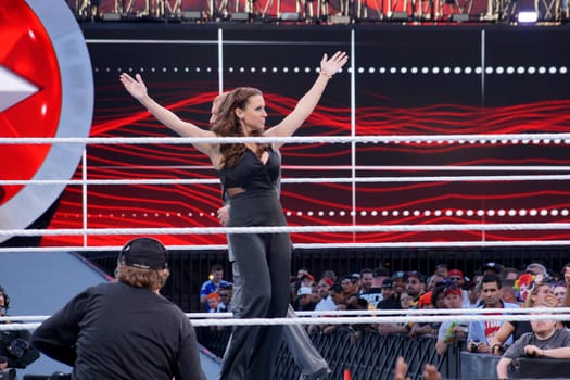 Santa Clara, California - March 29, 2015: Stephanie McMahon, the chief brand officer of WWE and the daughter of its chairman Vince McMahon, celebrates at Wrestlemania 31, the biggest event of the year for professional wrestling. She holds her arms in the air in a triumphant gesture, while the crowd cheers and boos at her performance. She is standing in the middle of the ring, surrounded by ropes and turnbuckles, at the Levi's Stadium.