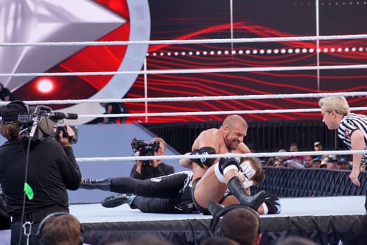 Santa Clara, California - March 29, 2015: During their match in the ring at Levi's Stadium for Wrestlemania 31, Triple H can be seen applying a chin lock on Sting as the referee, Charles Robinson, checks on him. Triple H appears to be grinning as he executes the move.