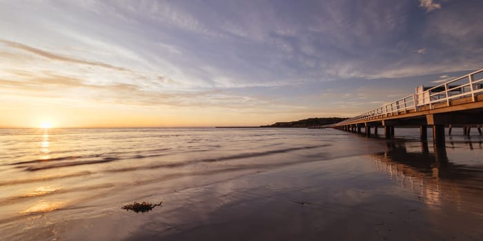 A view of the famous causeway leading to Granite Island Recreation Park at sunrise in Victor Harbor on a sunny autumn day in South Australia, Australia