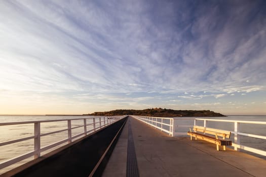 A view of the famous causeway leading to Granite Island Recreation Park at sunrise in Victor Harbor on a sunny autumn day in South Australia, Australia