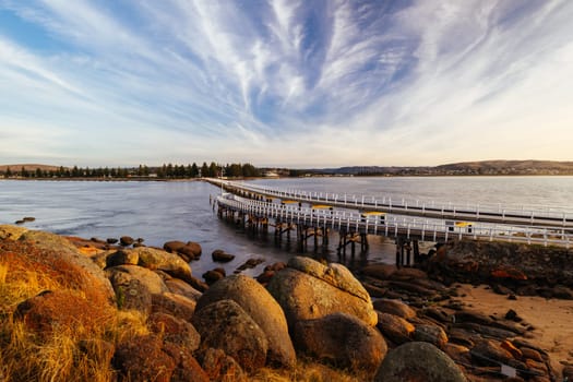 A view of the famous causeway leading to Granite Island Recreation Park at sunrise in Victor Harbor on a sunny autumn day in South Australia, Australia