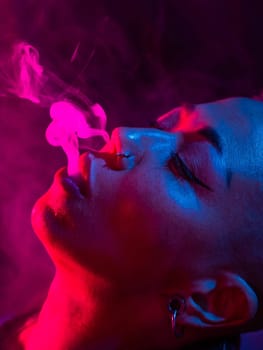 Asian woman with short haircut smoking in neon light. close-up portrait