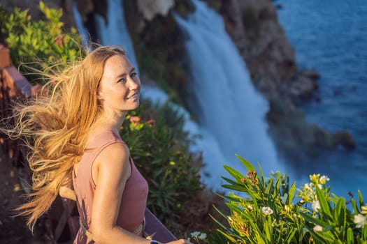 Beautiful woman with long hair on the background of Duden waterfall in Antalya. Famous places of Turkey. Lower Duden Falls drop off a rocky cliff falling from about 40 m into the Mediterranean Sea in amazing water clouds. Tourism and travel destination photo in Antalya, Turkey. Turkiye.
