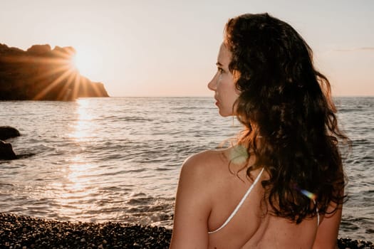 Young woman in swimsuit with long hair practicing stretching outdoors on yoga mat by the sea on a sunny day. Women's yoga fitness pilates routine. Healthy lifestyle, harmony and meditation concept.