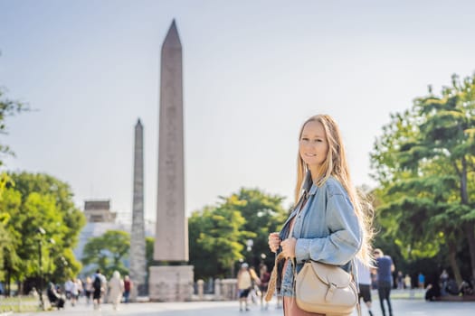 Woman Tourist in Istanbul against the background of Obelisk of Theodosius is the Ancient Egyptian obelisk of Pharaoh Thutmose III places in the Hippodrome of Constantinople, Turkey. Theodosius Dikilitasi.