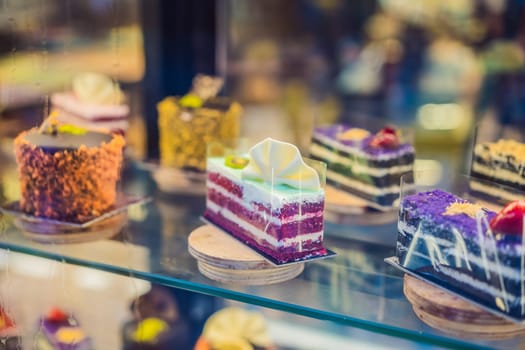 Different types of cakes in pastry shop glass display.