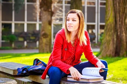 A young female college student study books outside of library.