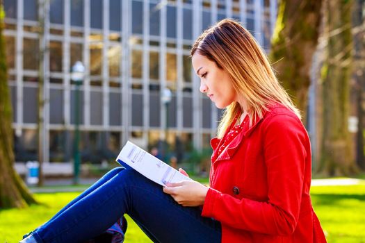 A young female college student study books outside of library.