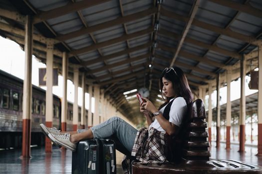 Image of A traveler checking message from her friend and waiting at train station. Travel concept.