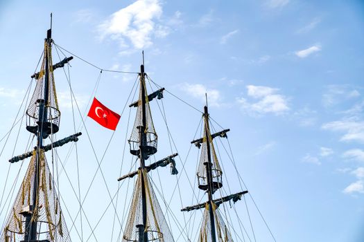 The masts of the ship with the Turkish flag on the background of the blue sky. The concept of travel and freedom