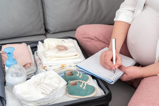 Pregnant woman writing packing list for maternity hospital at home