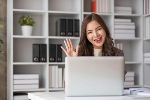 Cheerful business lady working on laptop in office, Asian happy beautiful businesswoman in formal suit work in workplace. Attractive female employee office worker smile...