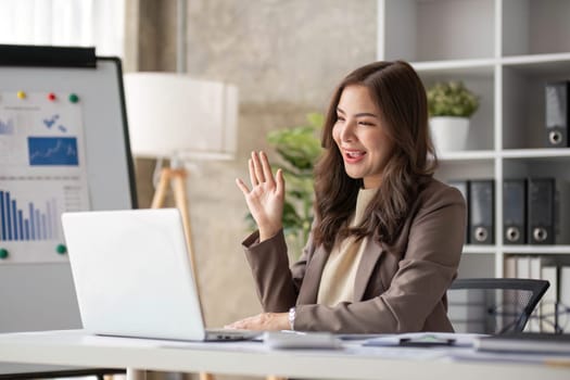 Cheerful business lady working on laptop in office, Asian happy beautiful businesswoman in formal suit work in workplace. Attractive female employee office worker smile...