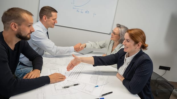 Business partners shake hands. Four business people are negotiating in the conference room