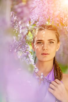 Woman wisteria lilac dress. Thoughtful happy mature woman in purple dress surrounded by chinese wisteria.