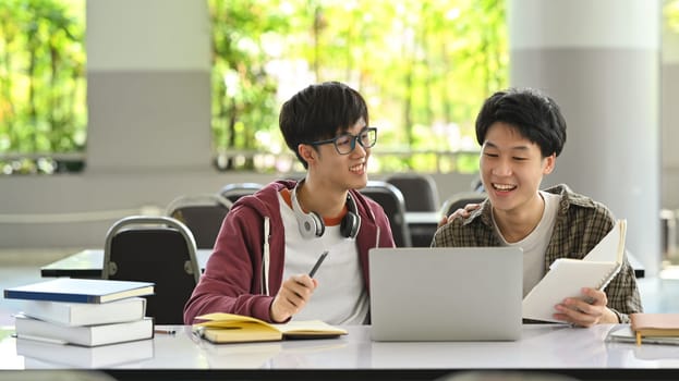 Two asian student man working together, preparing presentation on laptop. Education, technology and community concept.