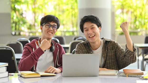 Two cheerful college students celebrating success together. Friendship, community and university concept.