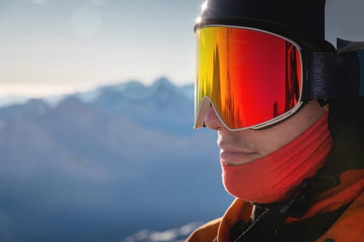 Close-up portrait of a guy holding skis in winter, he is wearing sportswear such as a helmet and sunglasses. winter, freedom, nature, sports, competitions. winter holidays in the alps, travel, hiking.
