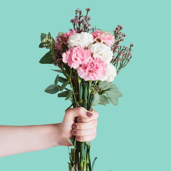 Flowers, bouquet and hands of woman on blue background for nature, spring and natural beauty. Romance mockup, present and girl with manicure holding botanical, floral or blossom gift in studio space.