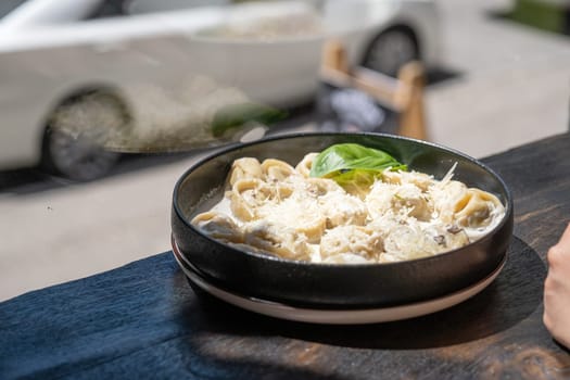 Ravioli in black plate on restaurant counter near window. Street background