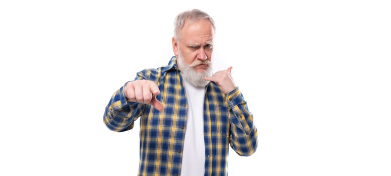 well-groomed mature gray-haired man with a beard in a shirt points his finger on a white background with copy space.