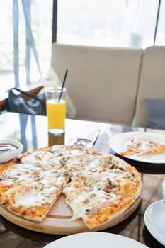 citalian chicken pizza with mozarella cheese on glass table in street cafe with soft seats and sofas, coffee and drinks around