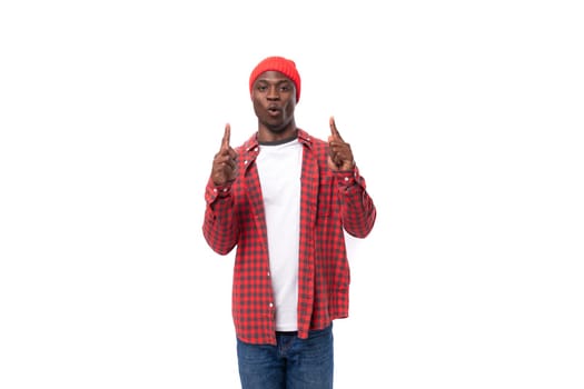 smart confident young american man in red cap and plaid shirt uses hands to gesticulate in advertising on white background with copy space.