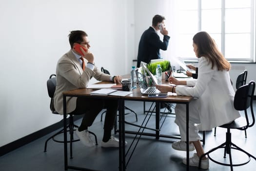 office staff talking on the phone while sitting at a common table.