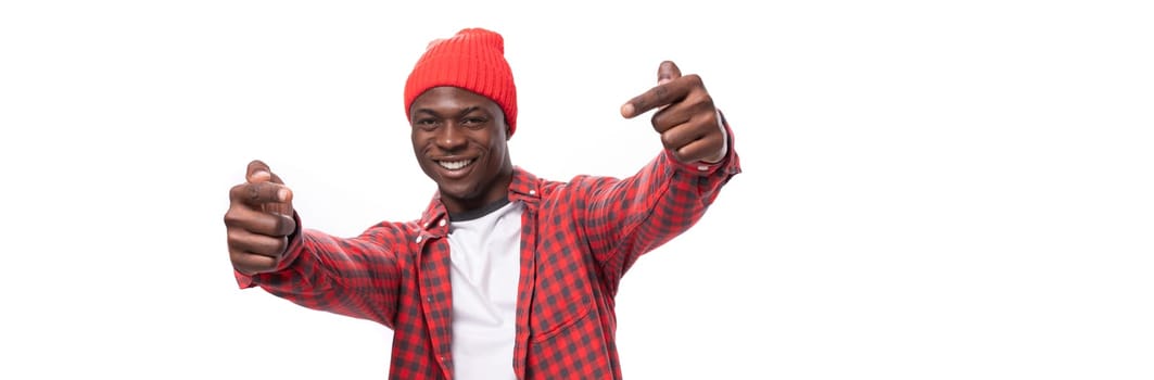 confident young ethnic african guy in stylish look pointing with index finger at promotional offer isolated on white background.