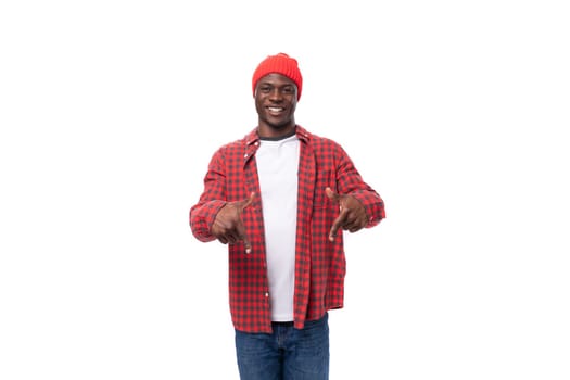 surprised positive young african man in cap and shirt telling news on isolated white background.