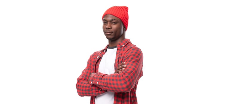successful handsome 30s black american man dressed in red shirt and cap on white studio background with copy space.