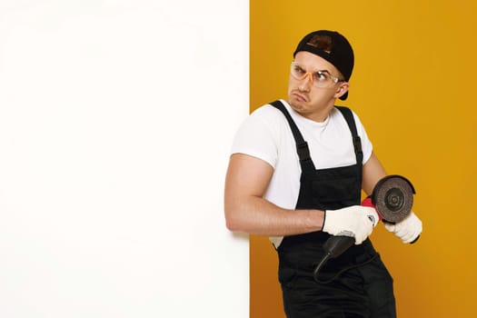 professional builder in work clothes works with cutting tool. worker handyman with grinder. copy space for text