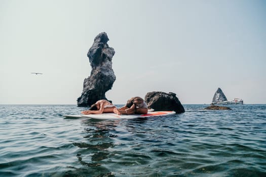 Woman sup yoga. Middle age sporty woman practising yoga pilates on paddle sup surfboard. Female stretching doing workout on sea water. Modern individual hipster outdoor summer sport activity