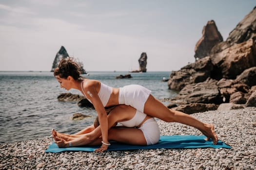 Woman sea yoga. Back view of free calm happy satisfied woman with long hair standing on top rock with yoga position against of sky by the sea. Healthy lifestyle outdoors in nature, fitness concept.