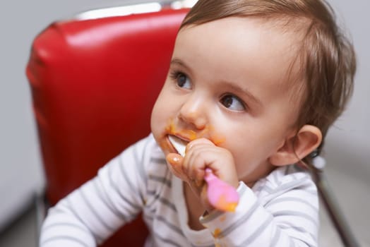 Shes such a cutie. a cute little baby sitting in a high chair eating