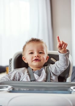 I need your attention. a cute little baby boy sitting in his feeding chair