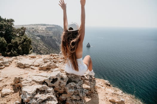 Woman travel sea. Young Happy woman in a long red dress posing on a beach near the sea on background of volcanic rocks, like in Iceland, sharing travel adventure journey