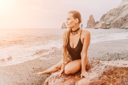 Side view a Young beautiful sensual woman in a mint long dress posing on a volcanic rock high above the sea during sunset. Girl on the nature on overcast sky background. Fashion photo