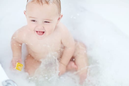 Splish splash. an adorable baby boy playing with a toy while bathing
