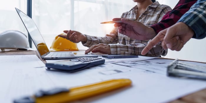 Architect and Engineer working with blueprints for architectural plan, engineer sketching a construction project, green energy concept.